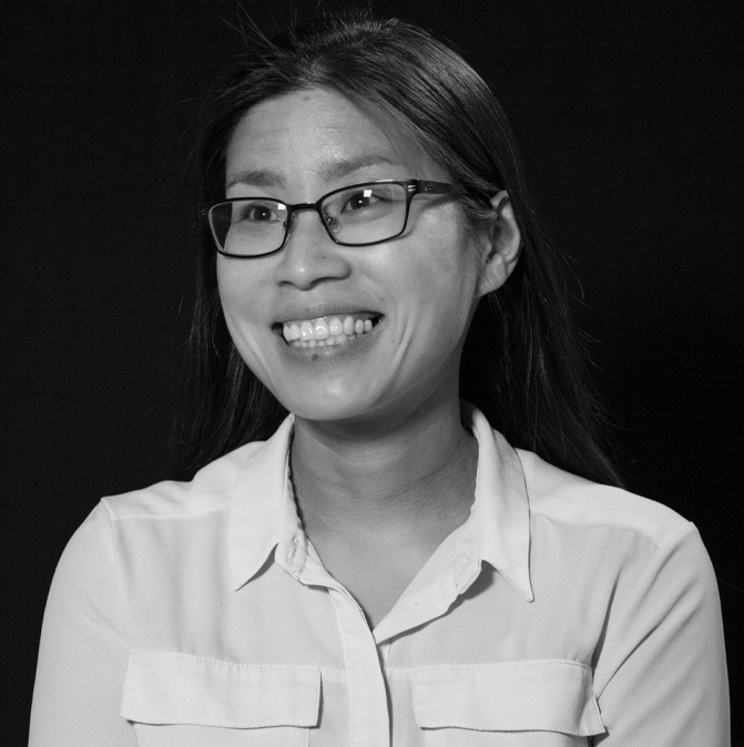 Black and white headshot of Faustina Hwang, a Taiwanese woman smiling, wearing glasses and a button-up shirt.